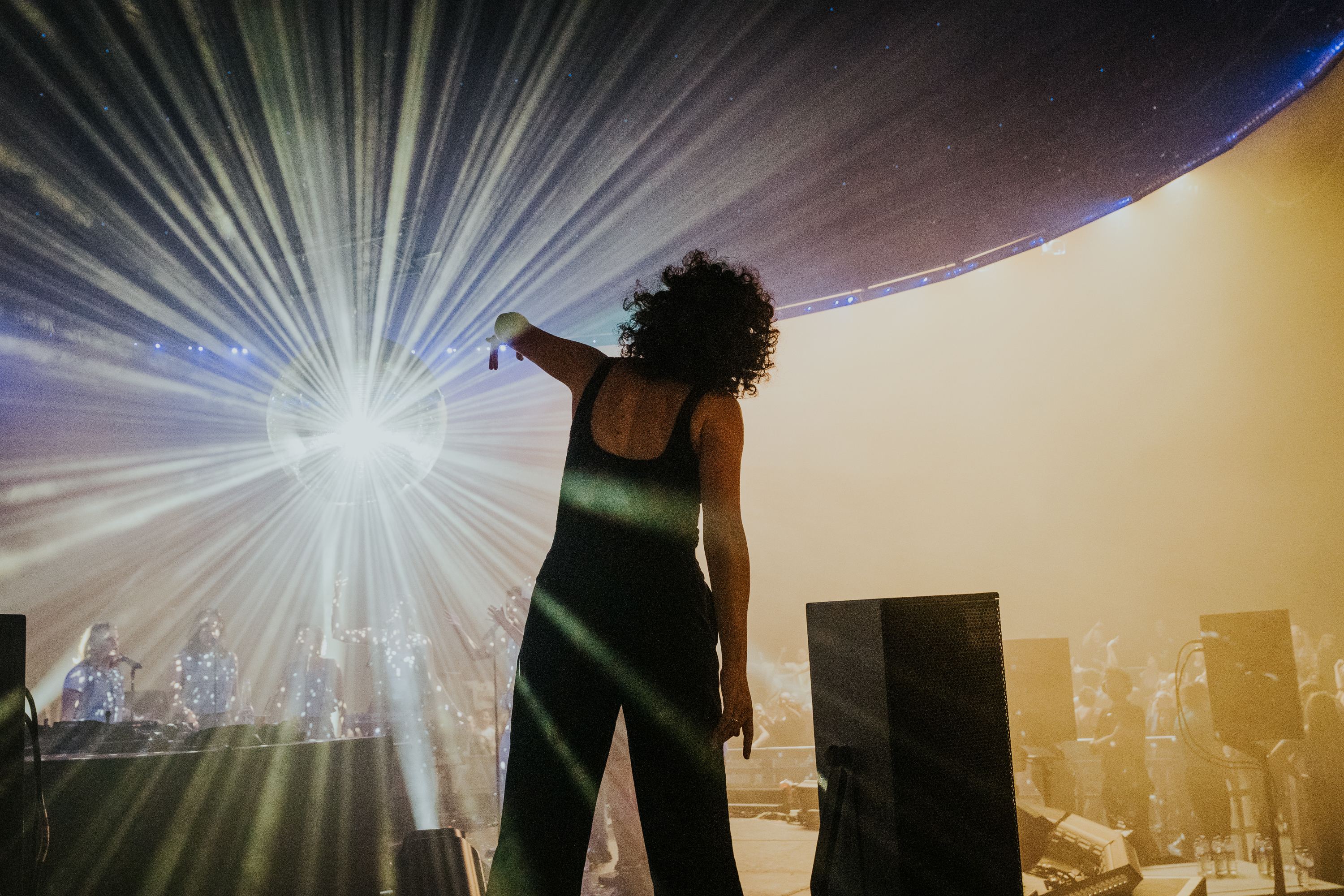 Annie silhouetted against the lights, pointing out at the crowd